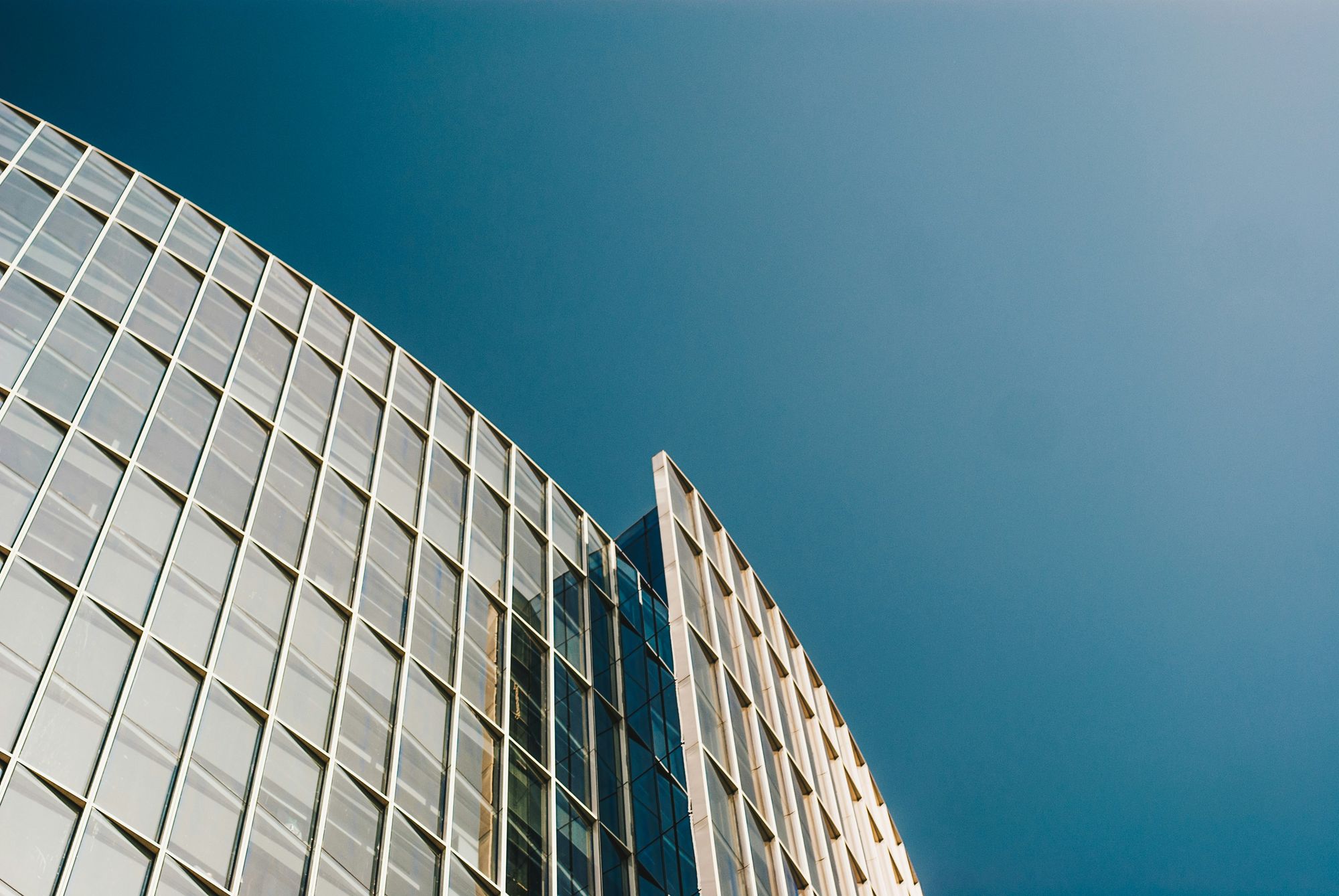 Fachada curva de vidrio de un edificio corporativo contra un cielo azul