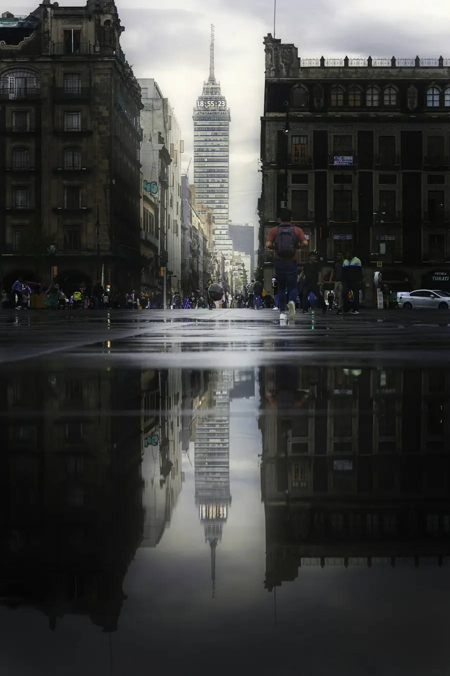 Calle del centro de la Ciudad de México reflejada en el piso mojado, con la Torre Latinoamericana al fondo